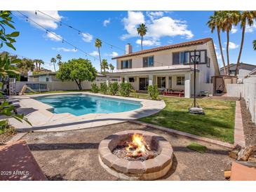 Inviting backyard featuring a sparkling pool, fire pit, green lawn, and mature landscaping perfect for outdoor living at 7469 E Timberlane Ct, Scottsdale, AZ 85258