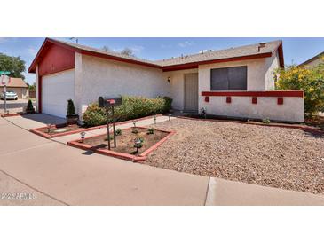 Charming single-story home with red trim, xeriscape landscaping, and a well-maintained lawn at 14235 N 26Th Dr, Phoenix, AZ 85023