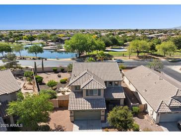 Beautiful aerial view of a two-story home with a lake nearby and well-maintained landscaping at 21019 N Sansom Dr, Maricopa, AZ 85138