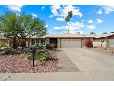 Charming single-story home featuring a two-car garage, desert landscaping, and a lush, green tree in the front yard at 3926 W Christy Dr, Phoenix, AZ 85029