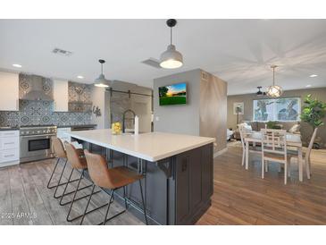 Open-concept kitchen featuring an island with bar seating and wood floors throughout the home at 4248 N Parkway Ave, Scottsdale, AZ 85251