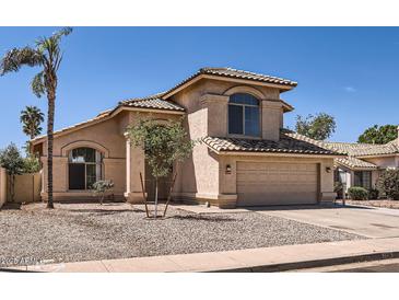 Charming home featuring a two-car garage, desert landscaping, and a classic Mediterranean-style tiled roof at 7239 E Madero Ave, Mesa, AZ 85209