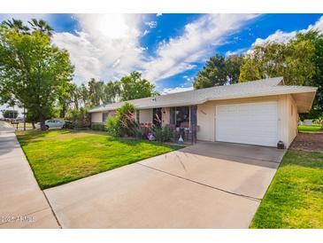 Single Gathering house with manicured lawn, mature plants, and a two-car garage at 17804 N Del Webb Blvd, Sun City, AZ 85373