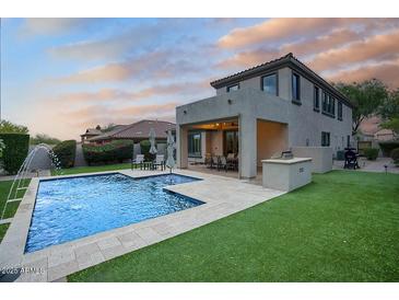 Exterior view of backyard showcasing a swimming pool, patio, and well-manicured lawn at 18515 N 97Th Way, Scottsdale, AZ 85255