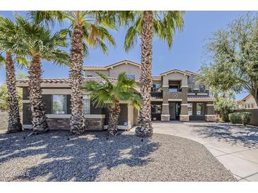 Elegant two-story home with desert landscaping and mature palm trees enhances curb appeal at 18581 E Aubrey Glen Rd, Queen Creek, AZ 85142