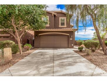 A two-story brown home with a two car garage and a well-manicured front yard at 20261 W Desert Bloom St, Buckeye, AZ 85326