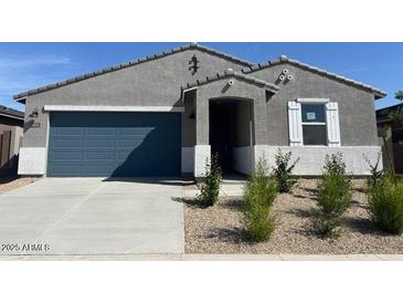 Charming single-story home featuring a blue garage door and low-maintenance desert landscaping at 22490 W Tonopah Dr, Surprise, AZ 85387