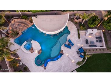 Aerial view of a custom pool with grotto, swim-up bar, water slide, and poolside fireplace and seating at 4281 S Iowa St, Chandler, AZ 85248