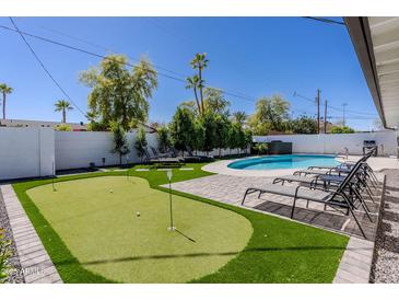 Beautiful backyard featuring a putting green, swimming pool, lounge chairs, and nice landscaping at 6413 E Parkview Dr, Scottsdale, AZ 85257