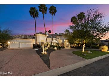 Elegant home featuring desert landscaping, a paver driveway, and a three-car garage at twilight at 11331 E Cochise Dr, Scottsdale, AZ 85259