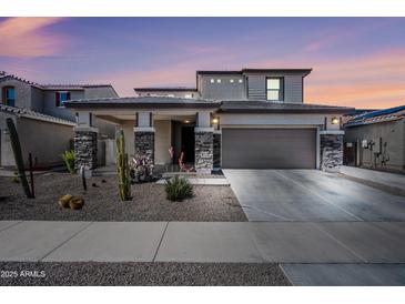 Two-story home featuring desert landscaping, a two-car garage, and a covered porch with stone accents at 16840 W Monroe St, Goodyear, AZ 85338