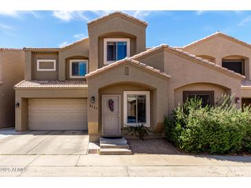 Inviting tan two-story home featuring a two-car garage, tiled roof, and well-manicured front yard with green shrubs at 2721 E Schiliro Cir, Phoenix, AZ 85032