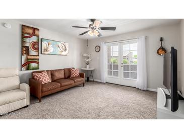 Inviting living room featuring a brown sofa, neutral walls, and access to the outdoors via French doors at 5995 N 78Th St # 2004, Scottsdale, AZ 85250