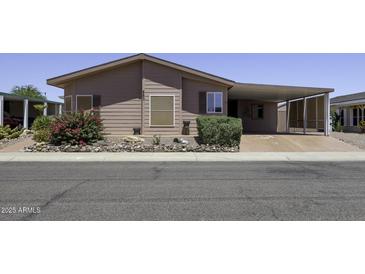 Charming single-story home with a covered carport and desert landscaping featuring a colorful flowering bush at 880 W Moon Shadow Dr, Casa Grande, AZ 85122