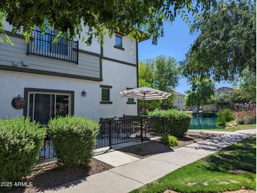Charming back patio with an umbrella and outdoor seating, overlooking the community pond and lush landscaping at 1814 E Bridgeport Pkwy # 103, Gilbert, AZ 85295