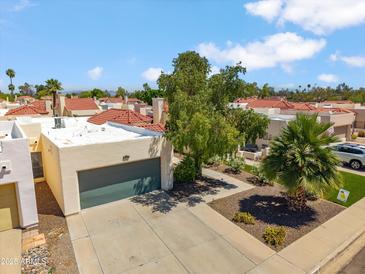 Charming single-story home featuring a gray garage door, red tile roof, and mature desert landscaping at 2170 E Alameda Dr, Tempe, AZ 85282