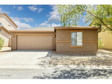 Tan single-story home features a two-car garage, desert landscaping, and a neutral color scheme at 2327 E Meadow Land Dr, San Tan Valley, AZ 85140