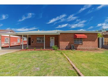 Charming brick home with a well-maintained lawn and covered parking at 2936 E Willetta St, Phoenix, AZ 85008