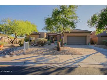 Charming single-story home with desert landscaping, mature trees, and a spacious driveway at 32472 N 68Th Pl, Scottsdale, AZ 85266