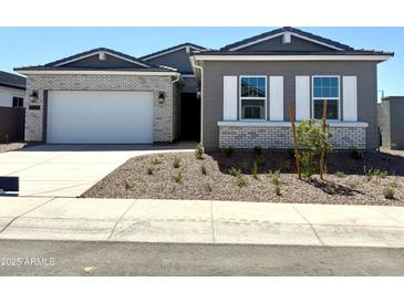 Charming single-story home featuring a brick and wood facade, a two-car garage, and desert landscaping at 35524 N Tin Ct, San Tan Valley, AZ 85144
