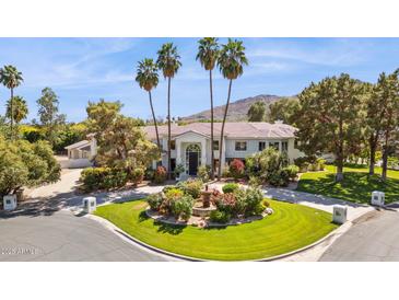 Stunning exterior view showcasing a beautiful home with a circular driveway, lush landscaping, and towering palm trees at 6467 E Sierra Vista Dr, Paradise Valley, AZ 85253