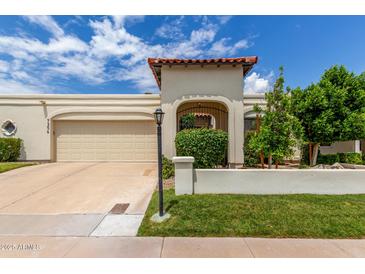 Charming single-story home with a beige stucco exterior, terra cotta tile accents, and a well-manicured front lawn at 7354 E San Miguel Ave, Scottsdale, AZ 85250