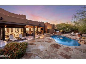 Inviting backyard pool and patio area with lush landscaping, comfortable seating, and a built-in outdoor kitchen at 7547 E Mary Sharon Dr, Scottsdale, AZ 85266