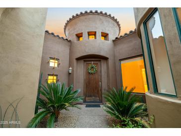 Inviting front entrance with a decorative wreath and well-maintained landscaping and neutral stucco at 19550 N Grayhawk Dr # 1117, Scottsdale, AZ 85255