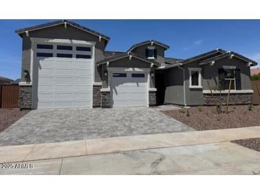 Charming home featuring a 3-car garage and inviting curb appeal with landscaped yard and stone accents at 23796 N 165Th Dr, Surprise, AZ 85387