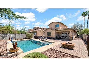 Backyard featuring a pool, fire pit, outdoor seating, and meticulously landscaped yard at 13256 N 153Rd Dr, Surprise, AZ 85379