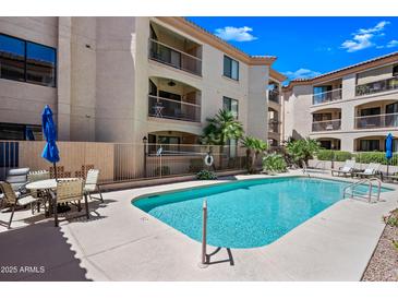 Community pool with clear blue water, lounge chairs, and palm trees near an apartment building with private balconies at 16631 E El Lago Blvd # 212, Fountain Hills, AZ 85268