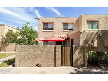 Charming condo featuring a private courtyard with red patio umbrellas and stylish wood gate at 8061 E Glenrosa Ave, Scottsdale, AZ 85251