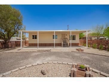 Charming single-story home featuring a covered porch, desert landscaping, and a gravel driveway under a clear blue sky at 9710 E Baywood Ave, Mesa, AZ 85208