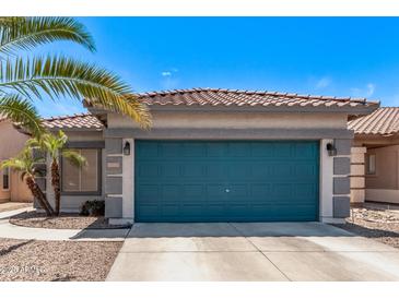 Attached garage with concrete driveway, desert landscaping and a well-maintained colorful blue door at 12913 W Columbine Dr, El Mirage, AZ 85335