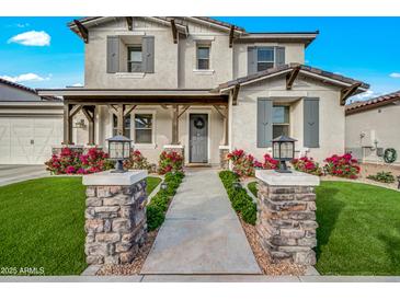Charming two-story home with a well-manicured lawn and inviting front porch and stone pillar detail at 22870 E Sonoqui Blvd, Queen Creek, AZ 85142