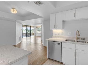 Bright kitchen area with wood floors, quartz countertops, stainless steel appliances, and balcony access at 4200 N Miller Rd # 325, Scottsdale, AZ 85251