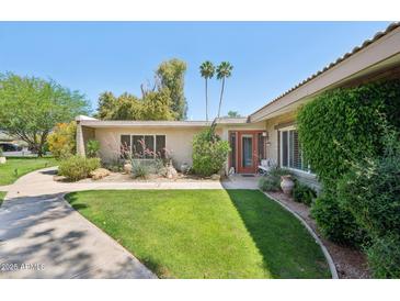 Charming single-story home with lush green lawn, mature trees, and a walkway leading to the front door at 4800 N 68Th St # 357, Scottsdale, AZ 85251
