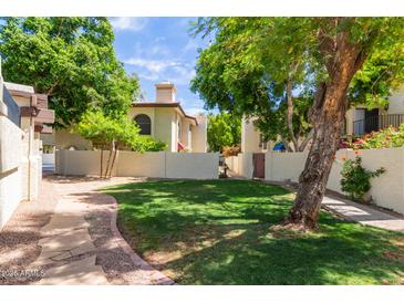 Well-maintained front yard featuring lush lawn and mature trees providing shade at 4818 E Hazel Dr # 1, Phoenix, AZ 85044