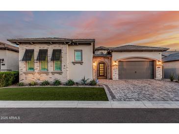 Charming single-Gathering home boasts a paver driveway, two-car garage, and manicured front yard with beautiful desert plants at 8127 E June St, Mesa, AZ 85207