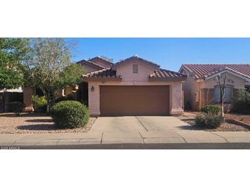 Traditional single Gathering home with a tile roof, brown garage door, desert landscaping, and a concrete driveway at 9967 W Devonshire Ave, Phoenix, AZ 85037