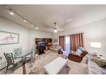 Comfortable living room with a glass top dining table, sofa, ceiling fan, and sliding glass door at 10401 W Loma Blanca Dr, Sun City, AZ 85351