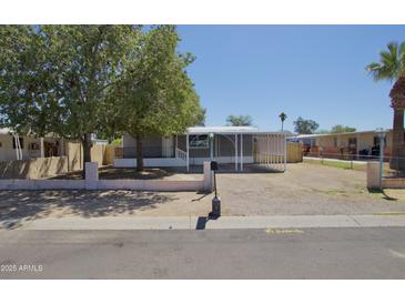 Charming single-story home features a covered parking, lush trees, and gravel landscaping at 319 S 90 Pl, Mesa, AZ 85208