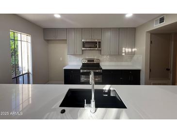 Updated kitchen with grey cabinets, black appliances, and modern backsplash at 5221 N 24Th St # 103, Phoenix, AZ 85016