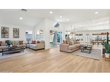 Bright and spacious living room with light hardwood floors, neutral tones, and modern furniture at 7204 W Mcrae Way, Glendale, AZ 85308