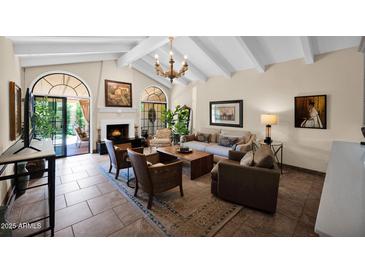 Inviting living room with a fireplace, neutral tones, and abundant natural light from the arched windows and doorway at 7955 E Chaparral Rd # 73, Scottsdale, AZ 85250