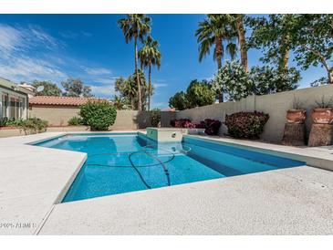 Inviting backyard pool featuring cool blue waters, white concrete trim, and lush landscaping with palm trees at 921 N Oxford Ln, Chandler, AZ 85225