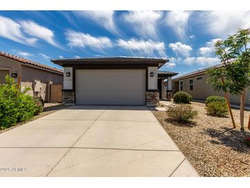 Home exterior featuring a two car garage with a neutral door and stone accents at 17437 W Via De Luna Dr, Surprise, AZ 85387