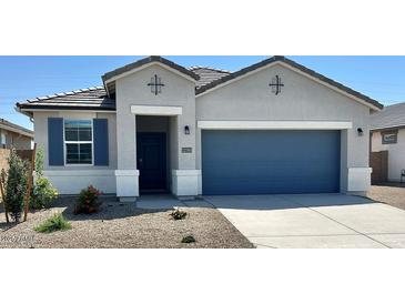 Charming single-story home with a blue two-car garage, neutral stucco and well-maintained landscaping at 22565 Rummler Ln, Maricopa, AZ 85138
