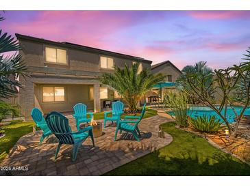 Inviting backyard featuring a fire pit with chairs, and lush landscaping with a tropical palm tree at 23523 N 117Th Dr, Sun City, AZ 85373