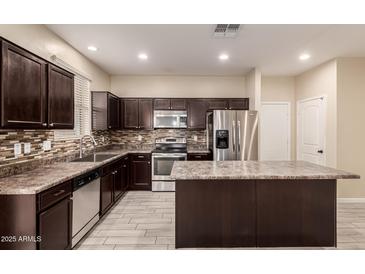 Modern kitchen with stainless steel appliances, island, and dark wood cabinetry at 7769 W Bonitos Dr, Phoenix, AZ 85035